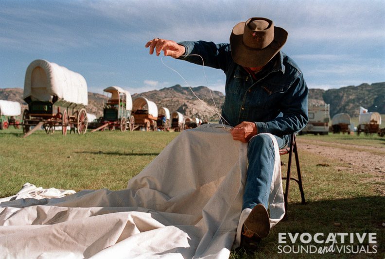 A Mormon Trail re-enactor mends his wagon cover at Independence Rock, Wyoming during the Sesquicentennial Celebration of the Mormon Trail in June 1997. Photo by Richard Alan Hannon